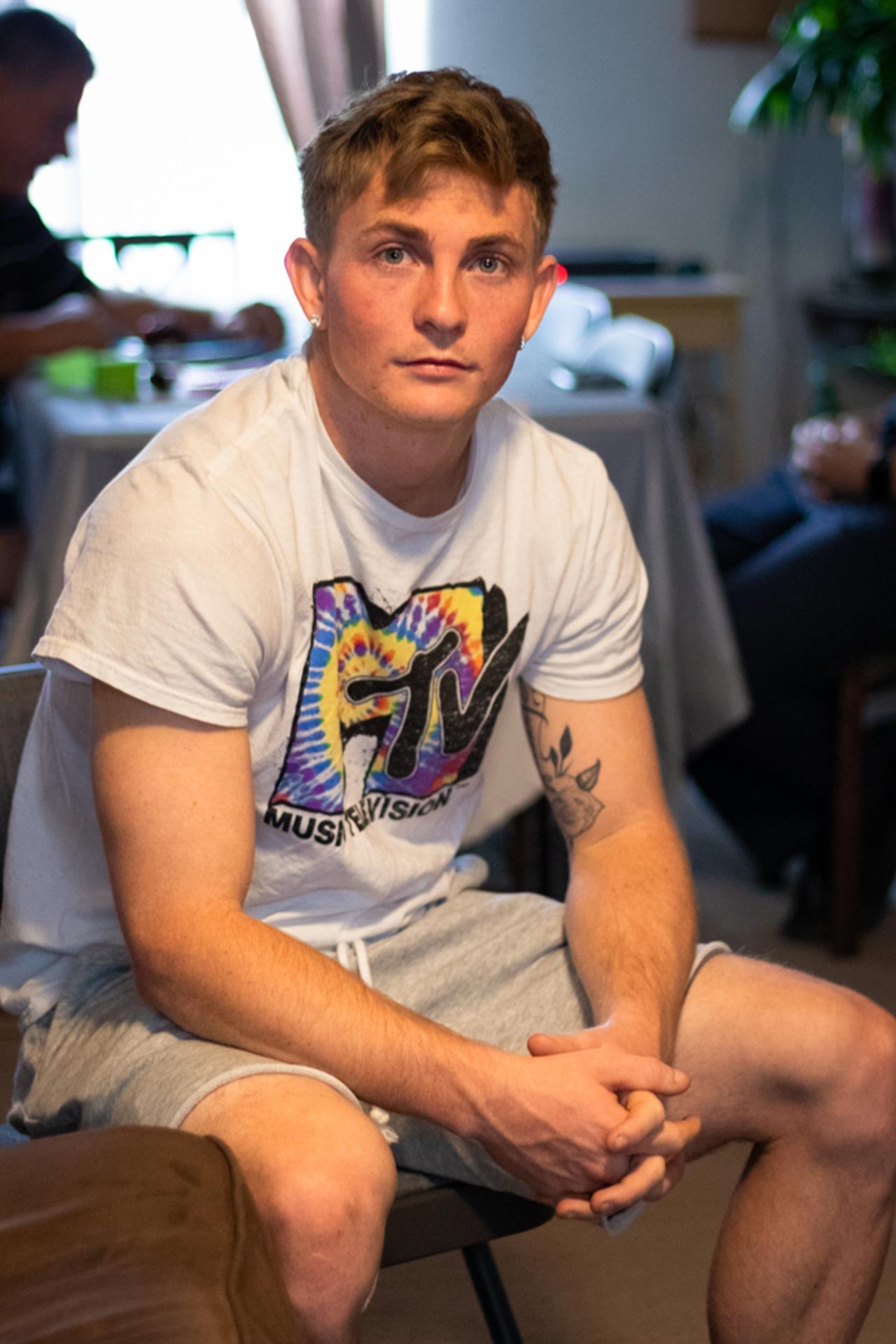 A candid photo of a young man looking into the camera while sitting in a chair.